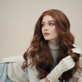 Woman with long ginger hair wig wearing white gloves against a plain background
